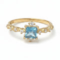 Jade18k yellow gold ring with a square-cut blue gemstone center and sparkling accent stones on a detailed band.