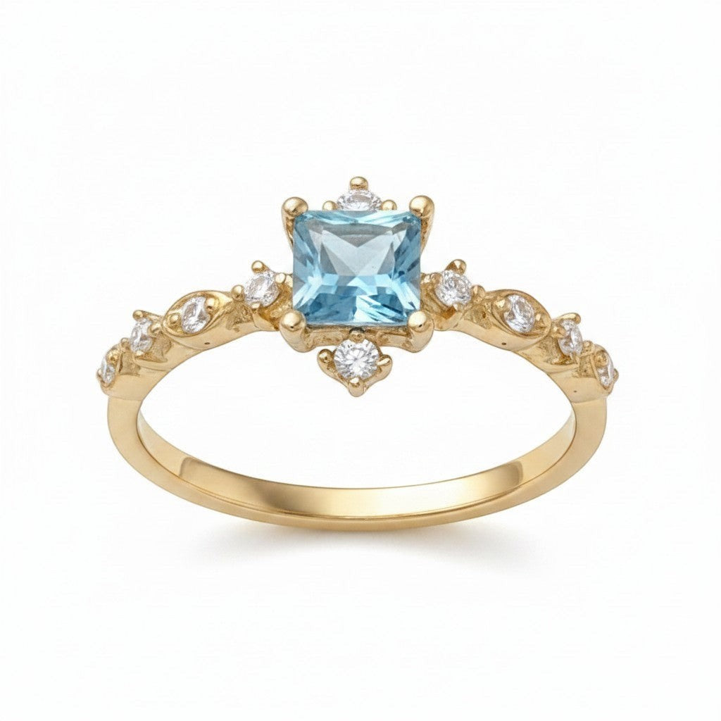 Jade18k yellow gold ring featuring a square-cut blue gemstone center with sparkling accent stones and intricate band detailing.