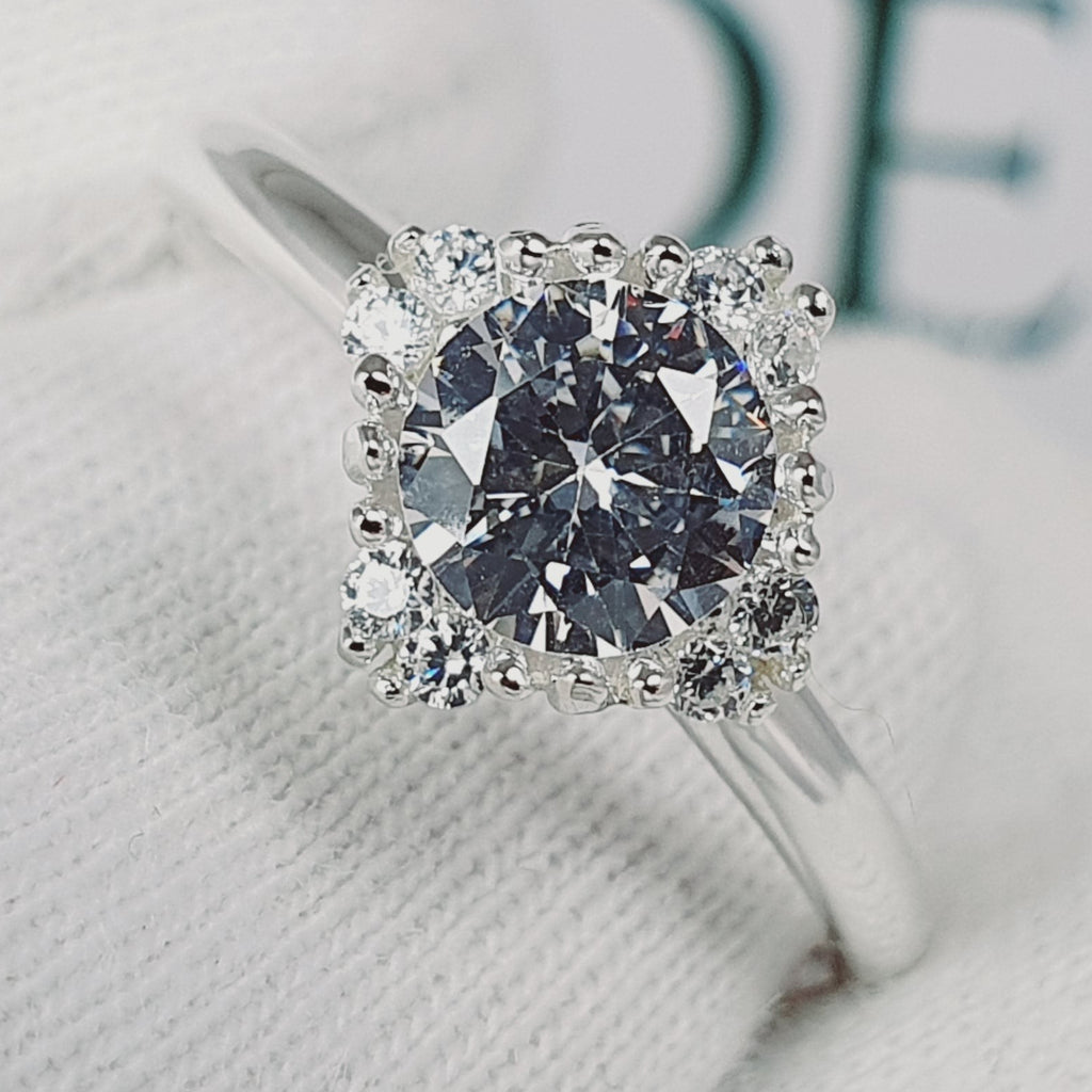 Jade18k Damelia engagement ring with a large central diamond surrounded by smaller diamonds in a silver band.
