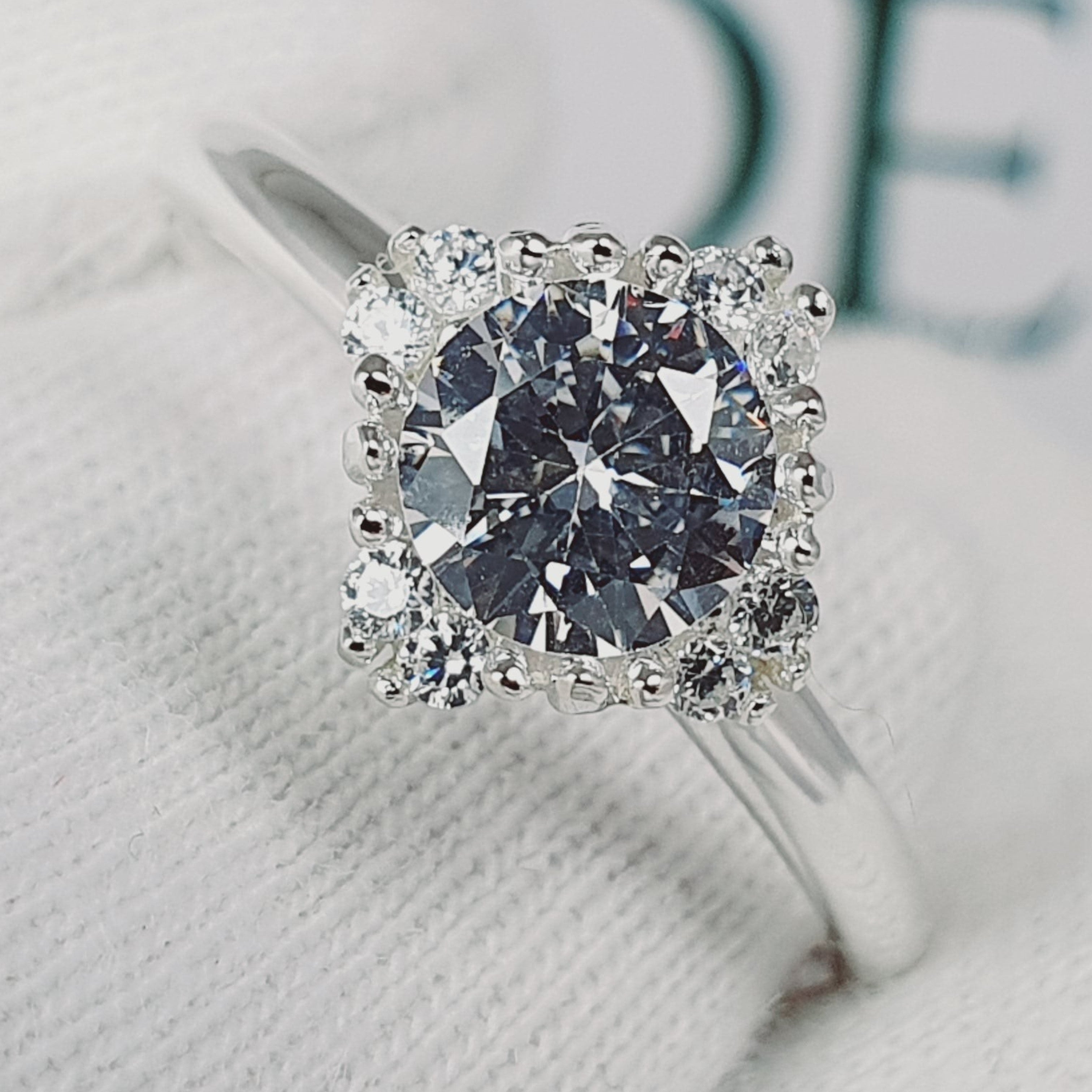 Jade18k Damelia engagement ring with a large central diamond surrounded by smaller diamonds in a silver band.