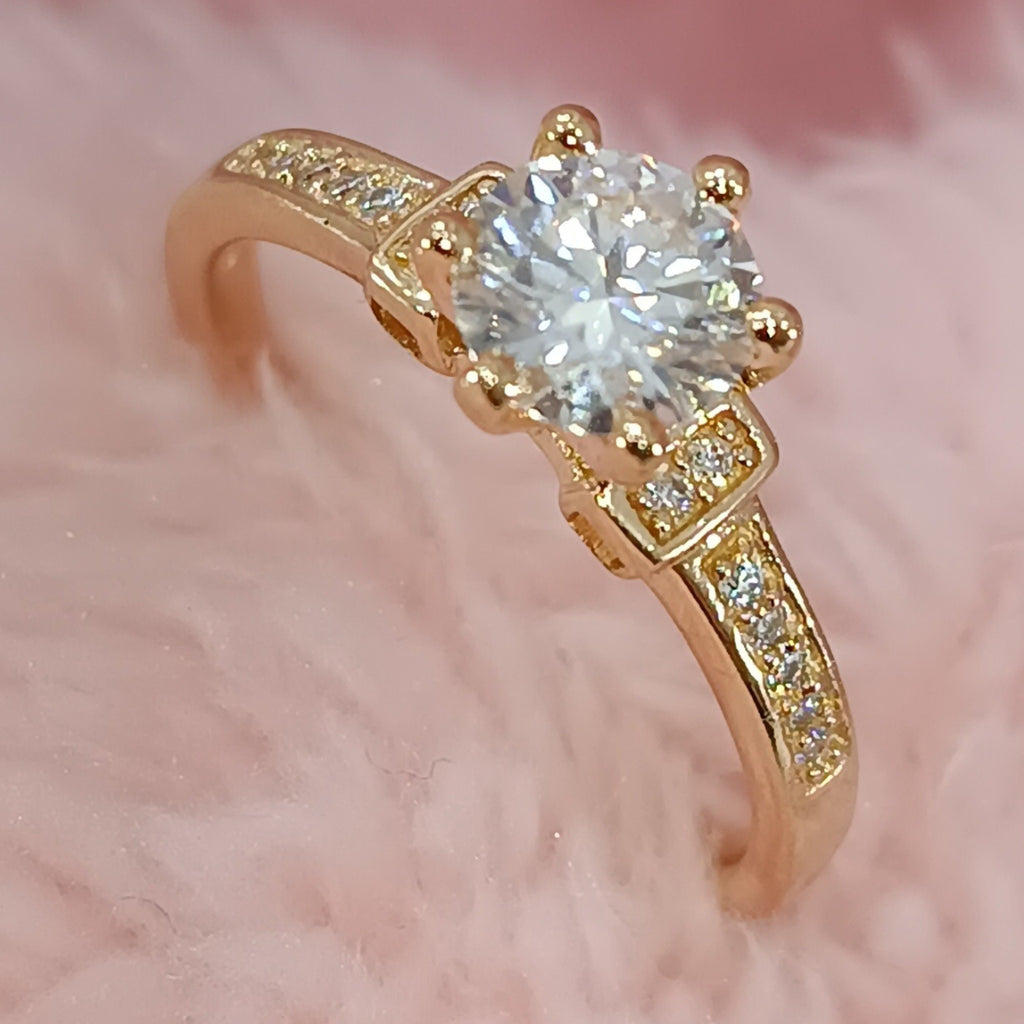 Jade18k Lú engagement ring in 18k orange gold with a central cubic zirconia and pavé stones on the band.