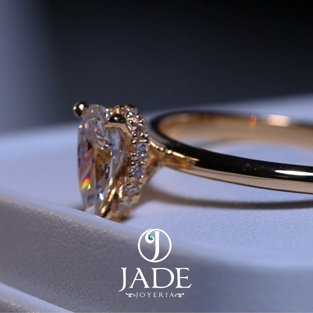 Jade18k engagement ring in 18k orange gold with a pear-cut cubic zirconia stone and small diamonds on the band.