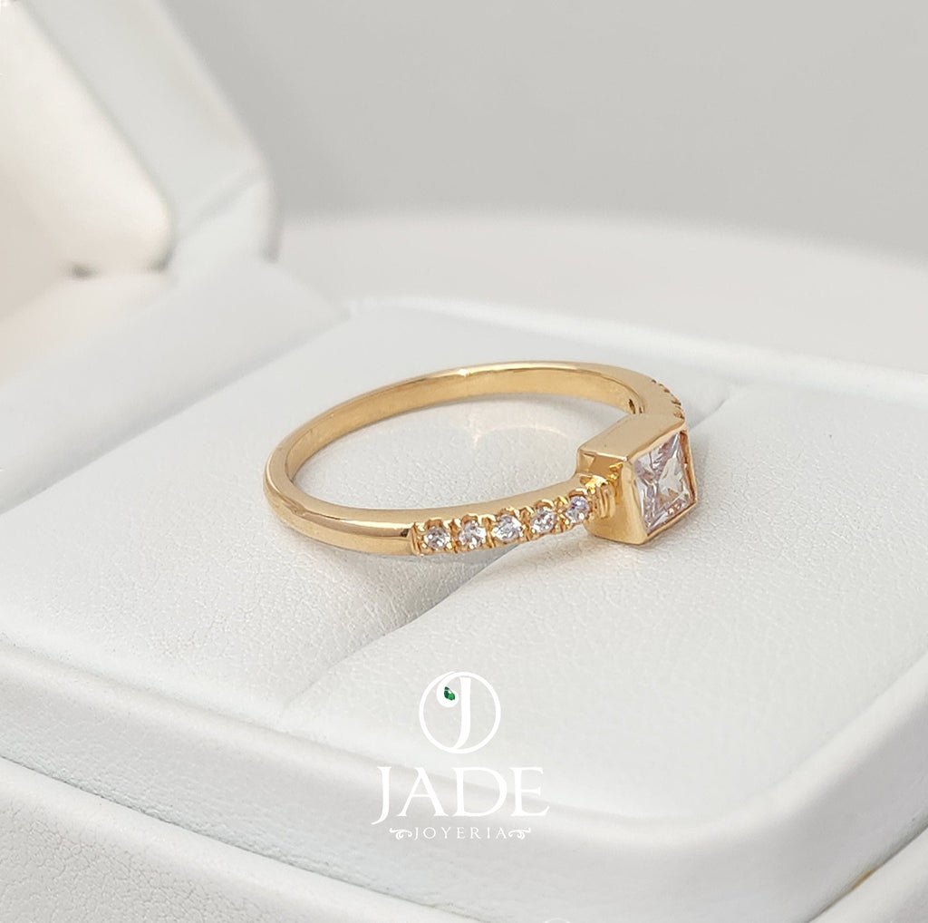 Jade18k Laura engagement ring in 18k orange gold with a princess-cut cubic zirconia and small stones on the band.