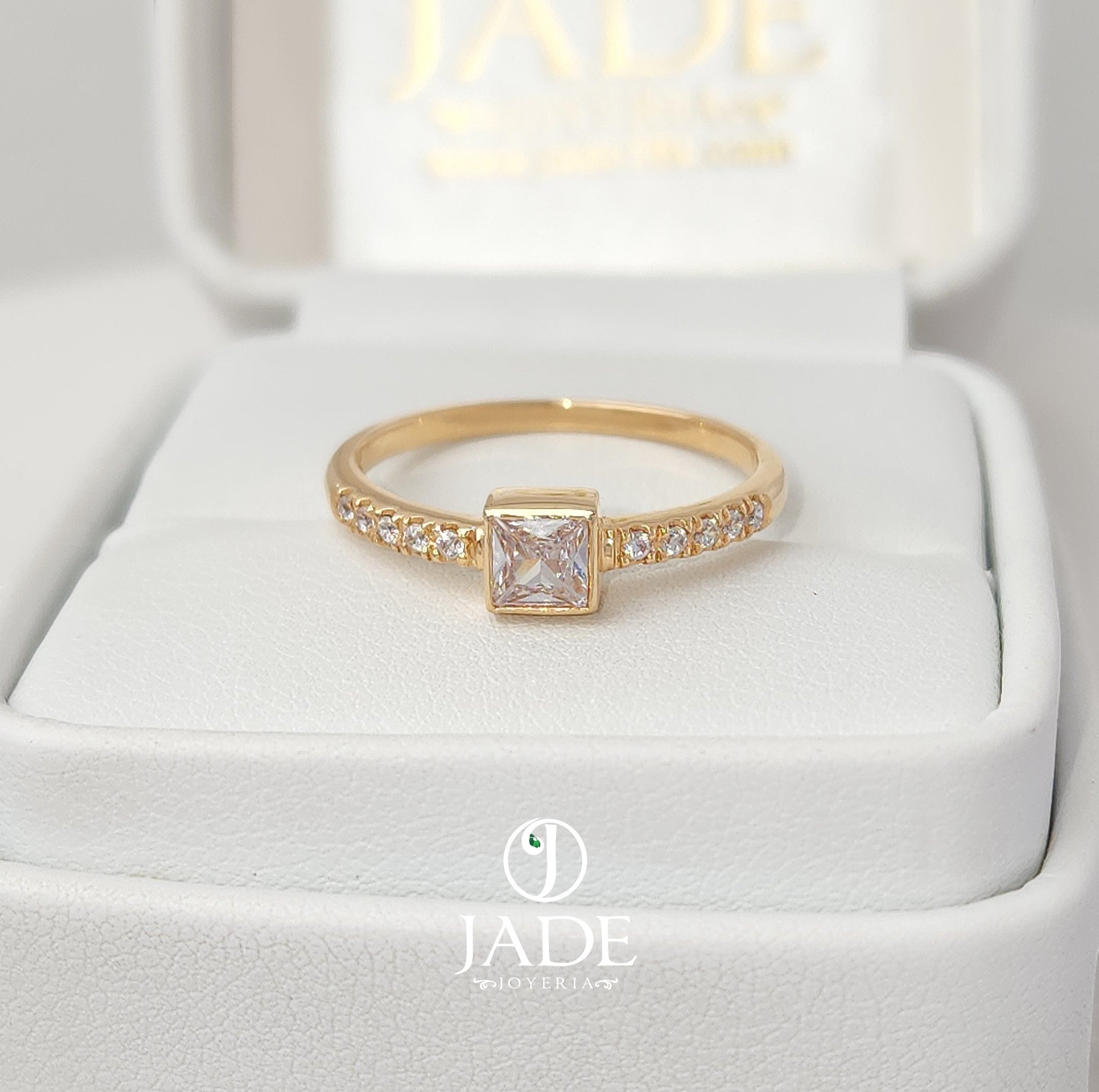 Jade18k engagement ring in 18k orange gold with a princess-cut cubic zirconia center stone and small cubic zirconia accents on the band.