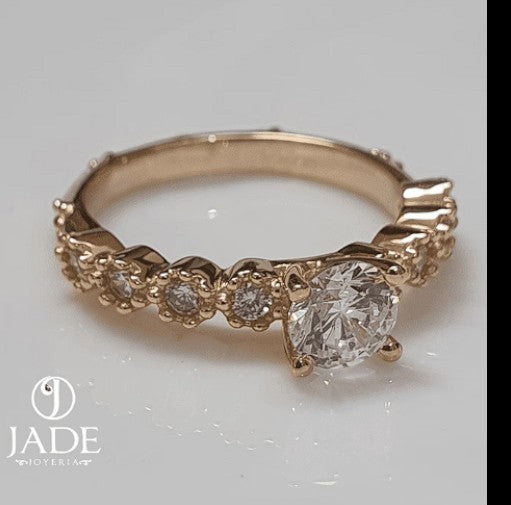 Jade18k Lians engagement ring in 18k orange gold with a central zircon stone and small stones along the band.