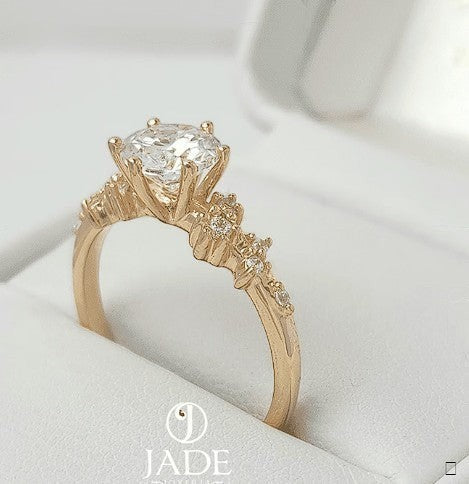 Jade18k Frisda 2 engagement ring in 18k orange gold with a central zircon stone and smaller stones along the band.