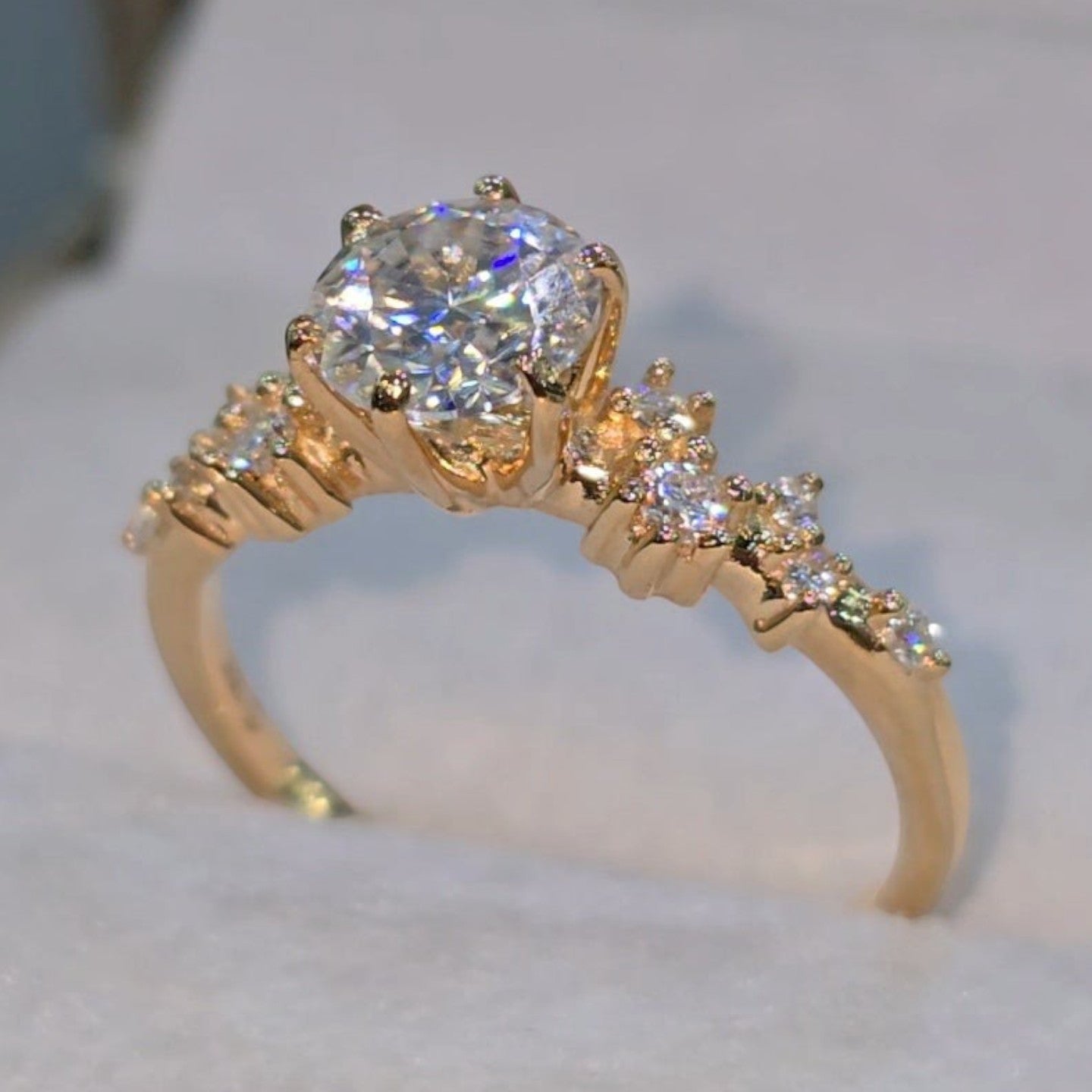 Jade18k 18k orange gold engagement ring with moissanite stones and a cluster of small stones on the band.