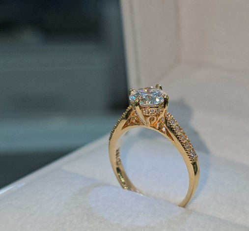Jade18k engagement ring with moissanite center stone and diamond accents on 18k orange gold band.