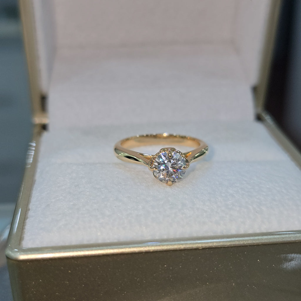 Jade18k 18k orange gold engagement ring with a round moissanite center stone and intricate detailing on the band.