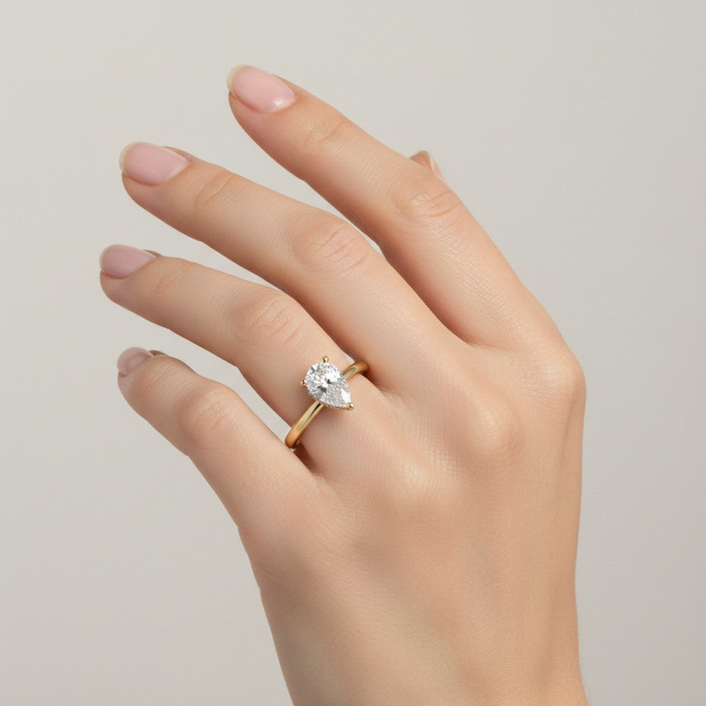 Jade18k Pegazo engagement ring in 18k orange gold with a pear-cut zircon stone and small accent stones.