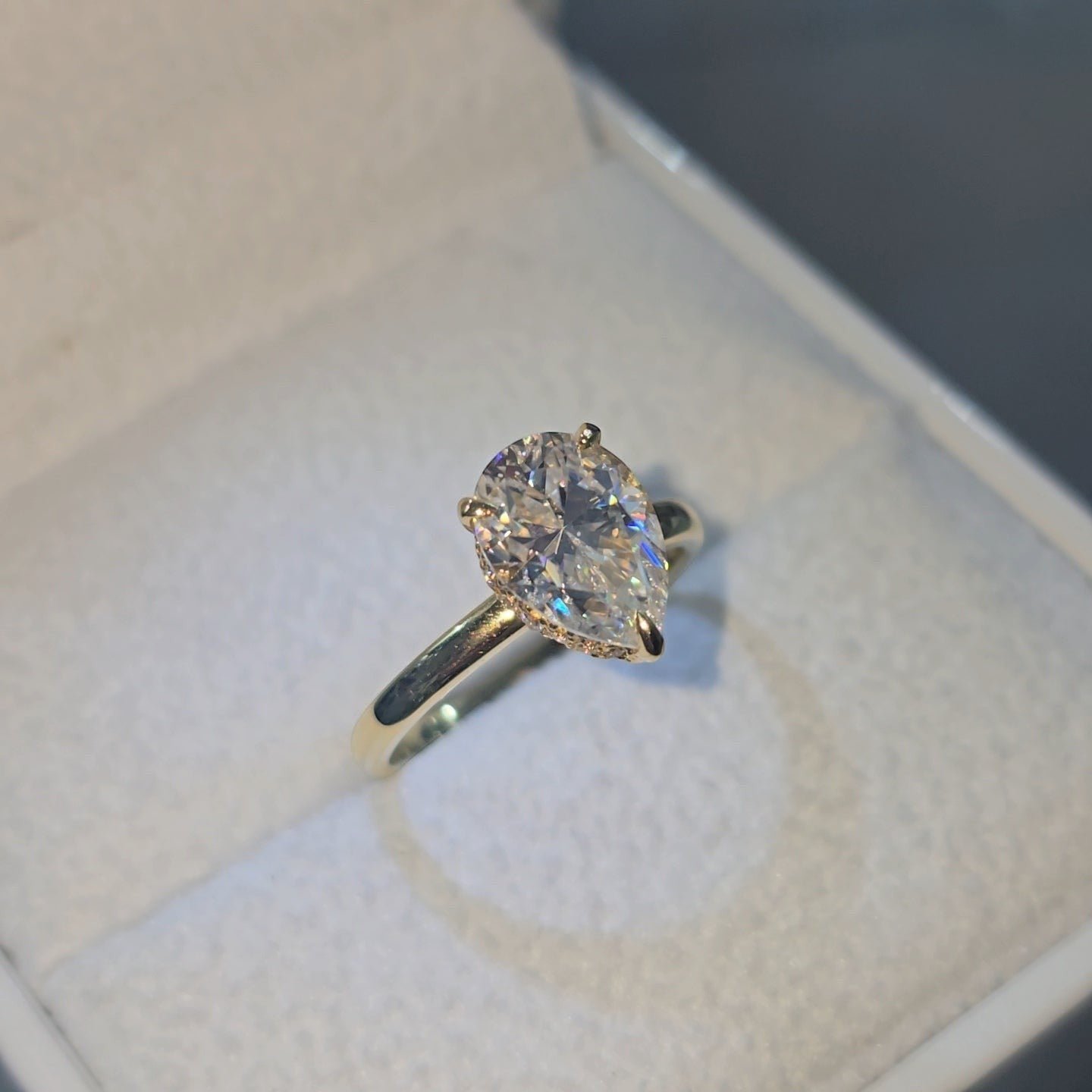 Jade18k 18k yellow gold engagement ring with a pear-cut Moissanite center stone and pavé band.