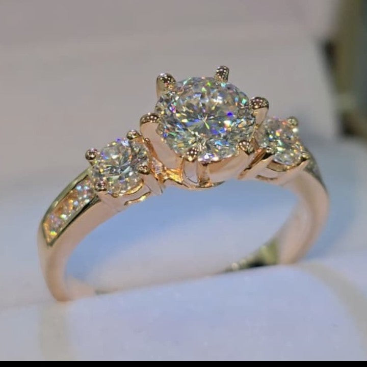 Jade18k 18k rose gold ring with three sparkling moissanite stones, center stone larger than side stones.