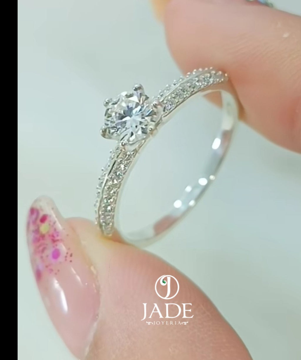 Jade18k engagement ring in silver with a central round-cut diamond and pave-set stones on the band.