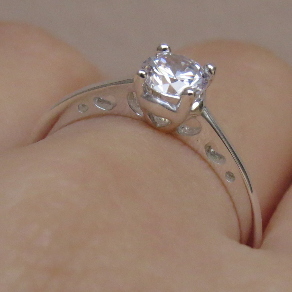 Jade18k sterling silver solitaire ring with a clear cubic zirconia stone and heart cutouts on the band.