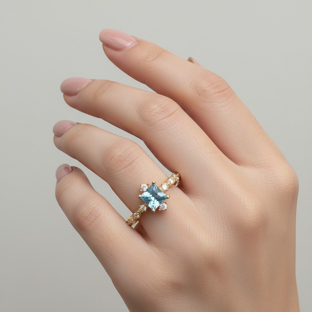 Jade18k yellow gold ring featuring a square-cut blue gemstone center with sparkling accent stones and intricate band detailing.