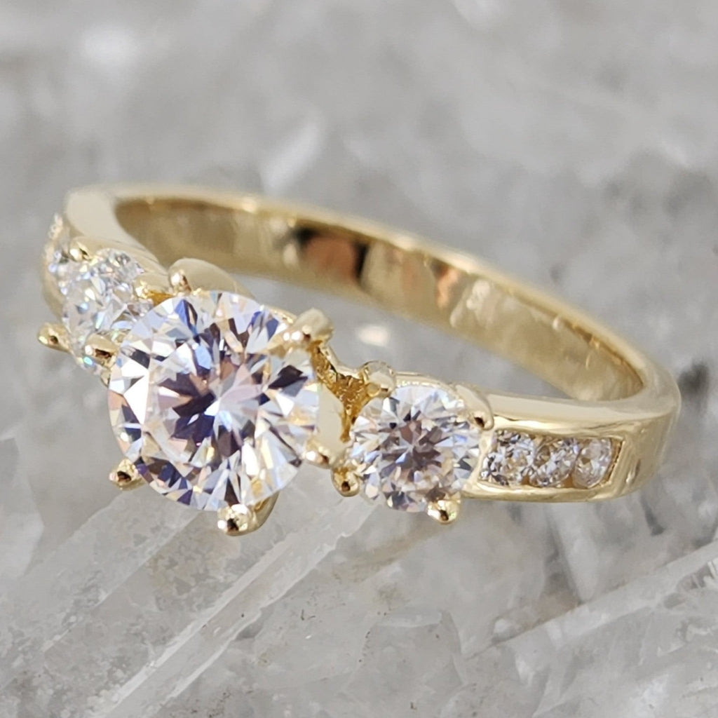 Jade18k yellow gold three-stone engagement ring with round and baguette-cut stones.