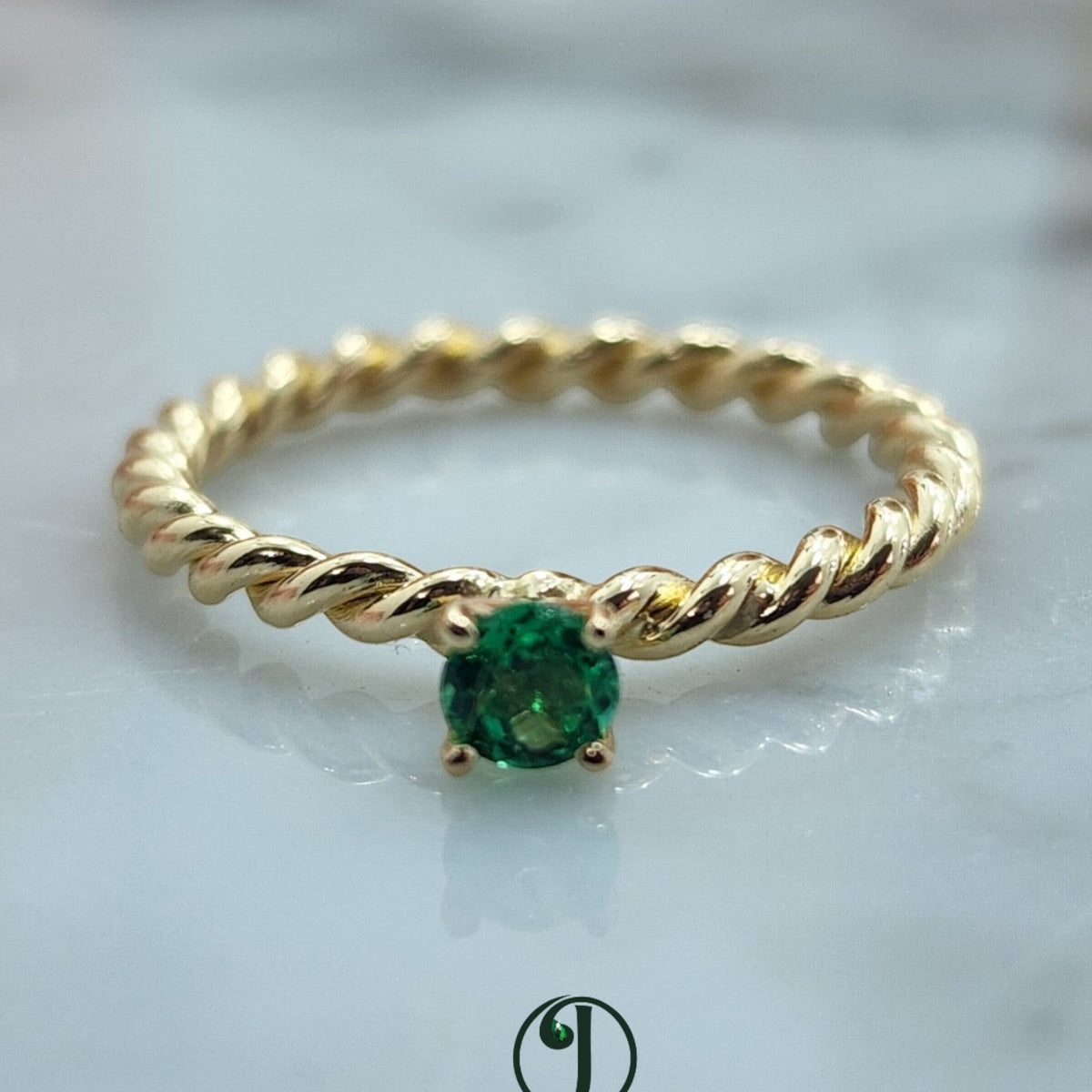 Jade18k twisted band solitaire ring with a round green emerald centerpiece, crafted from 14k yellow gold.