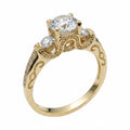 Jade18k Legado Divino 18k yellow gold engagement ring with a central zircon stone and smaller stones on the band, featuring intricate scrollwork.