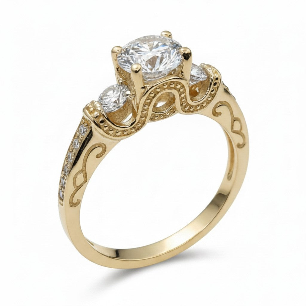 Jade18k Legado Divino 18k yellow gold engagement ring with a central round-cut cubic zirconia and two smaller side stones. Features intricate scrollwork and pave detailing on the band.
