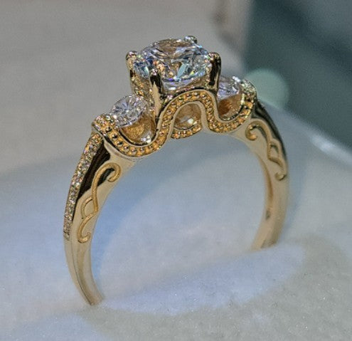 Jade18k 18k yellow gold engagement ring with a central round-cut zircon and smaller stones on the band. Features ornate detailing.