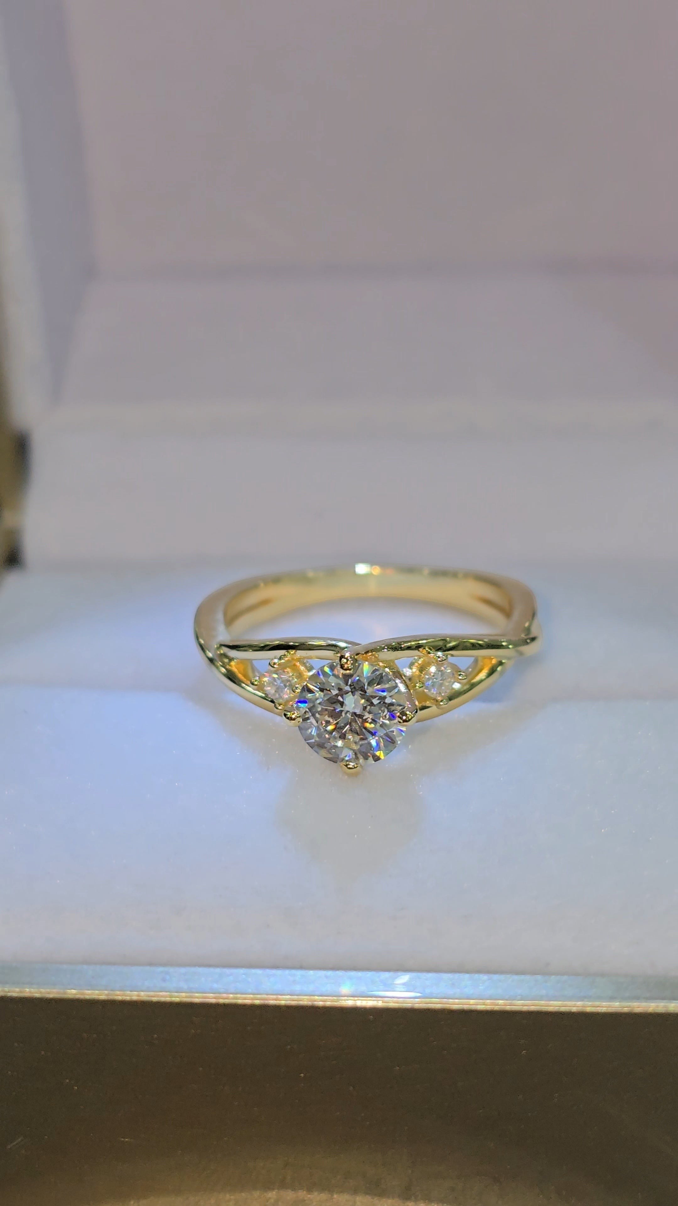 Jade18k Amor Puro engagement ring in yellow gold with a central moissanite and accent stones. Twisted band design.