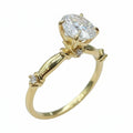 Jade18k 18k yellow gold engagement ring with a large oval moissanite center stone and small accent diamonds on the band.