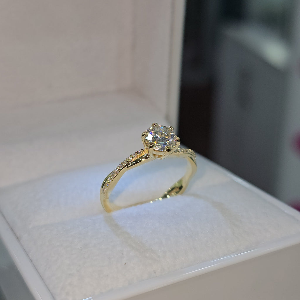 Jade18k yellow gold 18k engagement ring with a central moissanite stone and a twisted band with small diamonds.