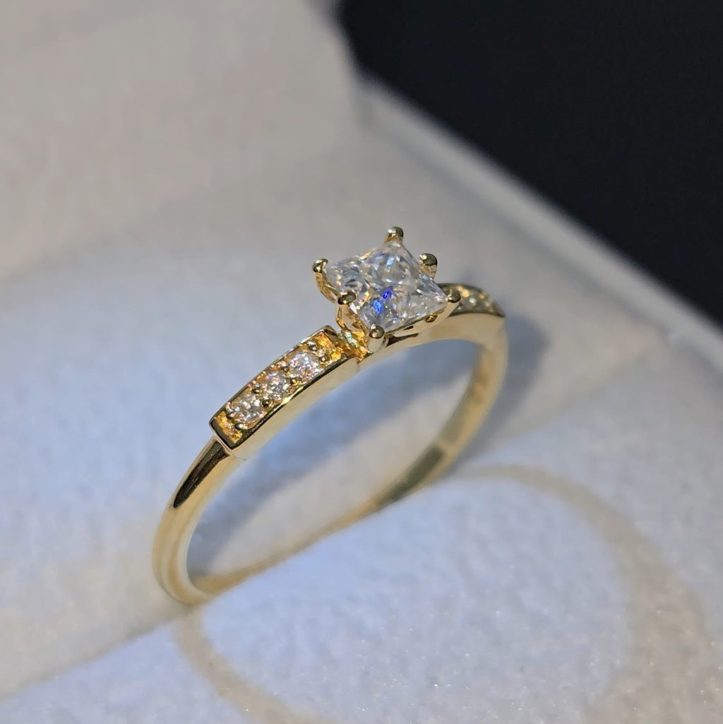 Jade18k 18k yellow gold engagement ring with princess-cut moissanite center stone and small accent stones on band.