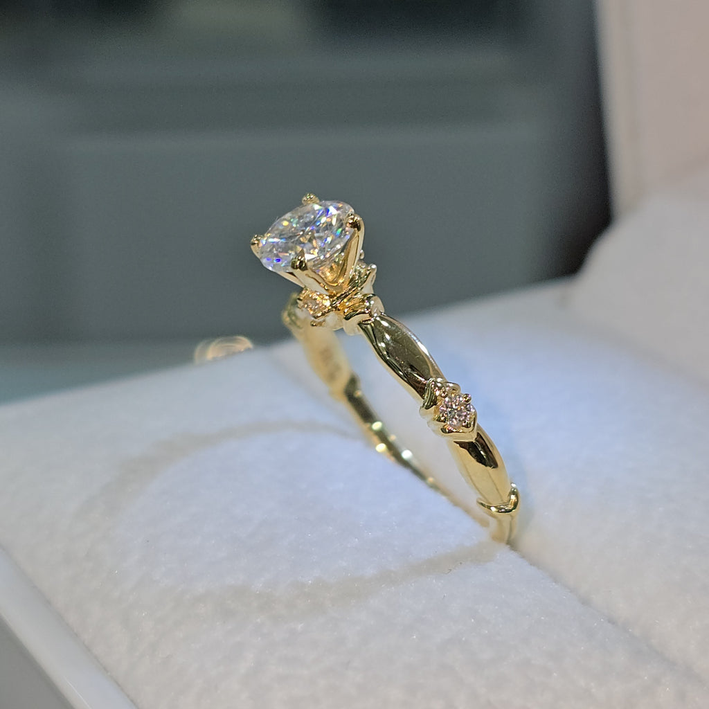 Jade18k 18K yellow gold engagement ring with a central moissanite stone and delicate detailing on the band.
