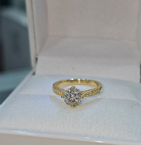 Jade18k 18k yellow gold engagement ring with a round moissanite center stone and small accent stones on the band.