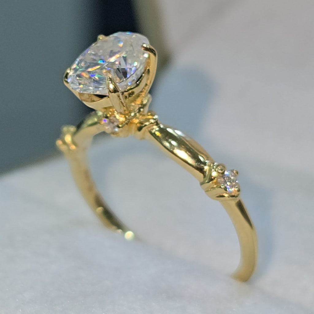 Jade18k 18k yellow gold engagement ring with a large oval moissanite center stone and small accent stones on the band.