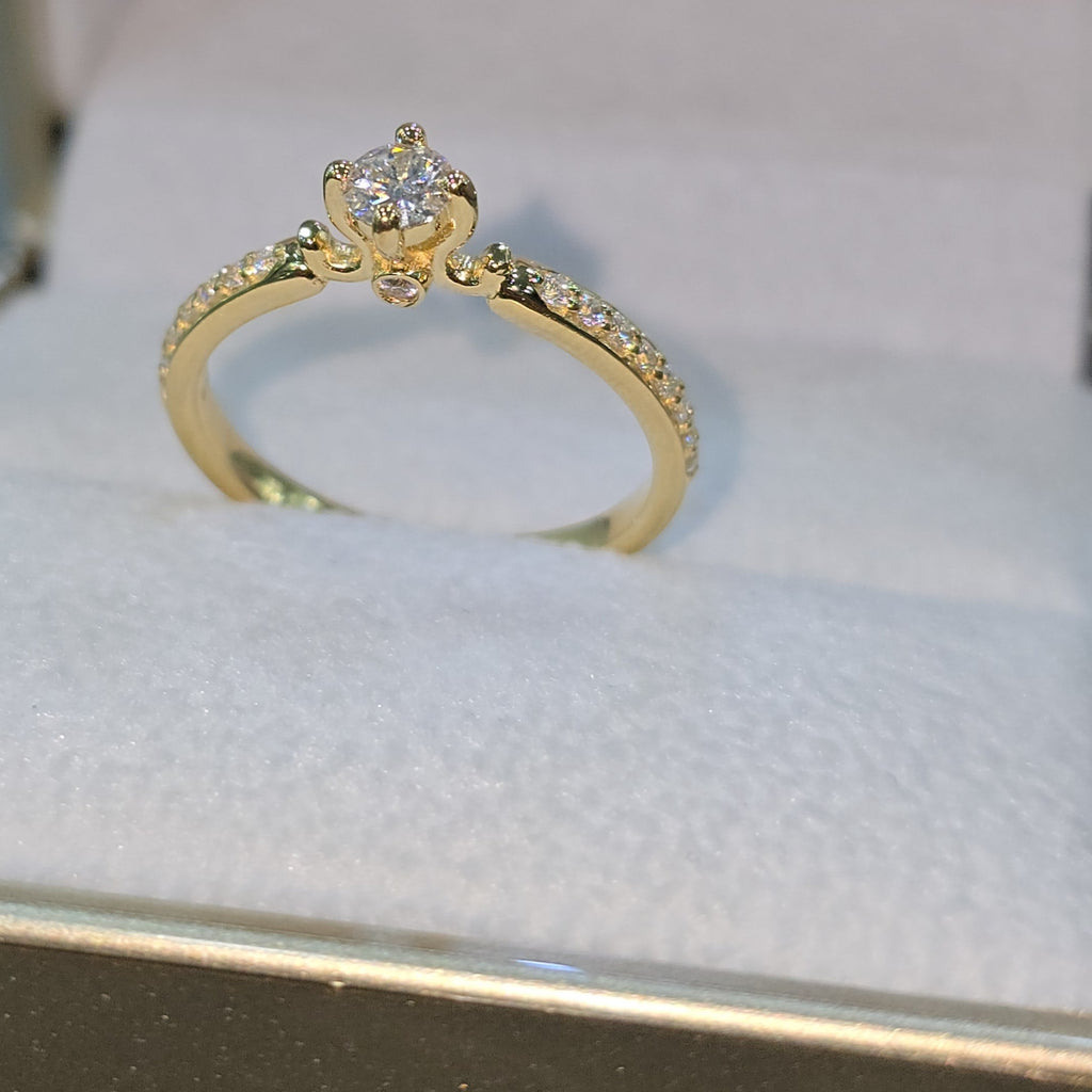 Jade18k 18k yellow gold engagement ring with a central moissanite stone and pavé-set stones along the band.