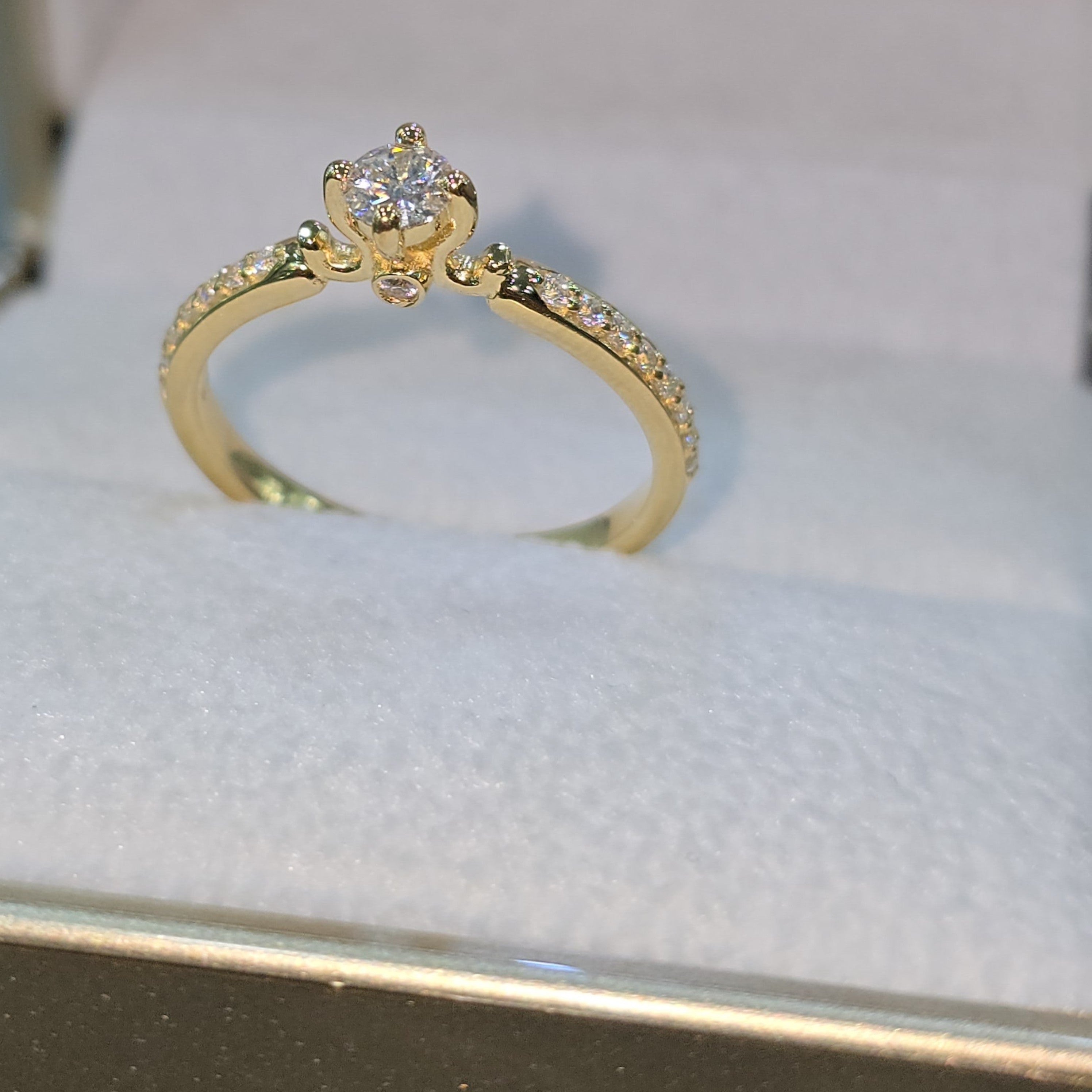Jade18k 18k yellow gold engagement ring with a central moissanite stone and pavé-set stones along the band.