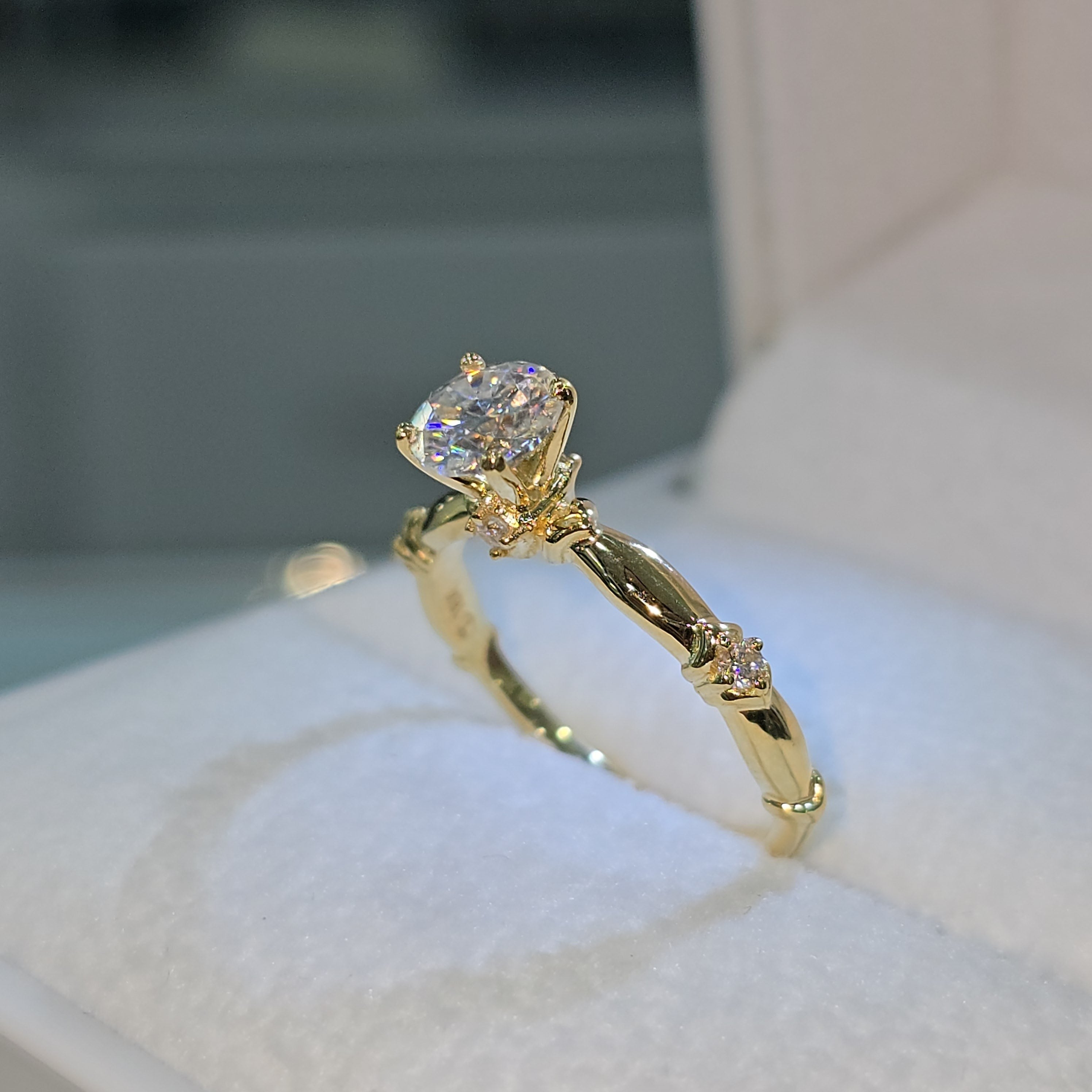 Jade18k 18K yellow gold engagement ring with a central moissanite stone and small accent stones on the band.