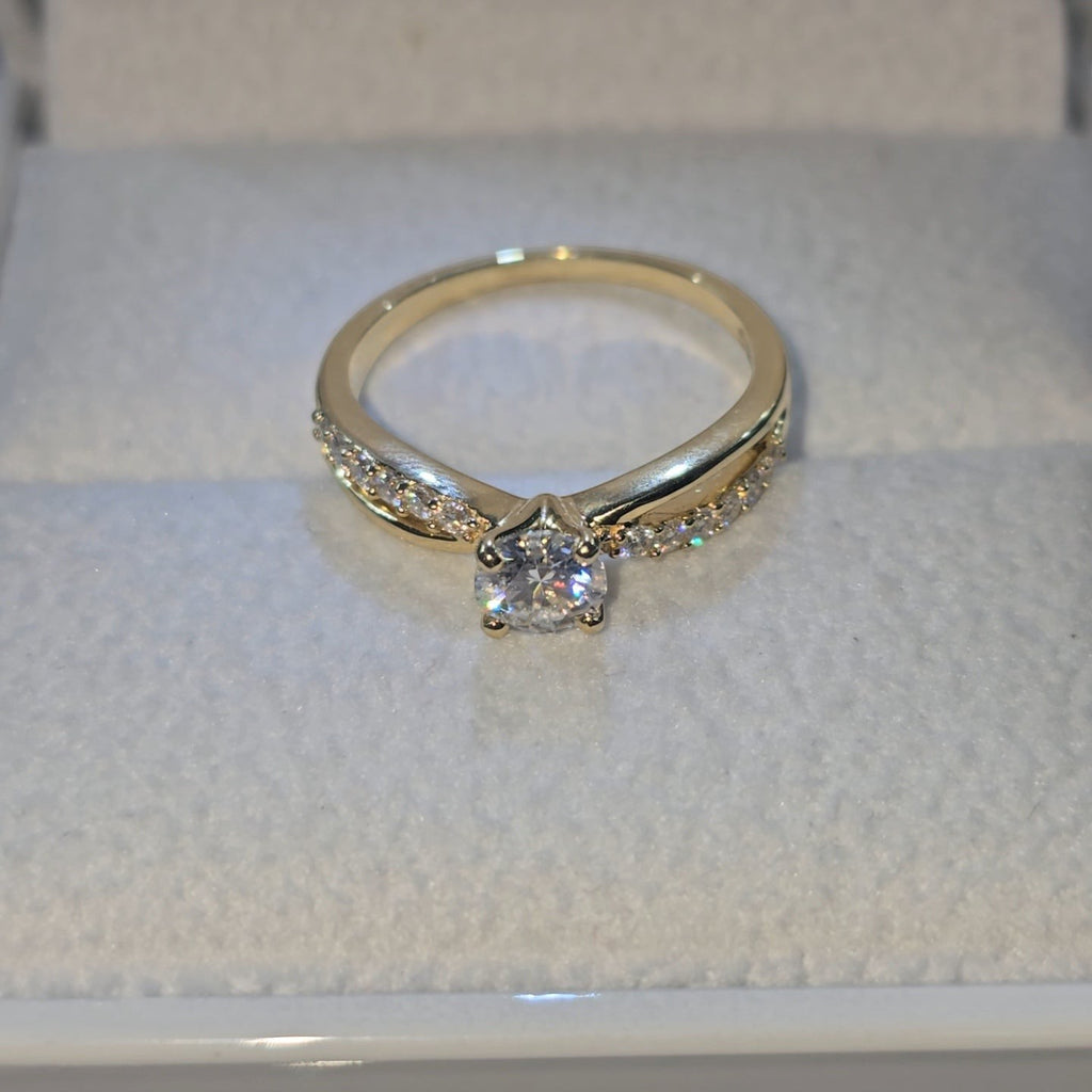 Jade18k 18k yellow gold engagement ring with a central moissanite stone and small stones on the band.