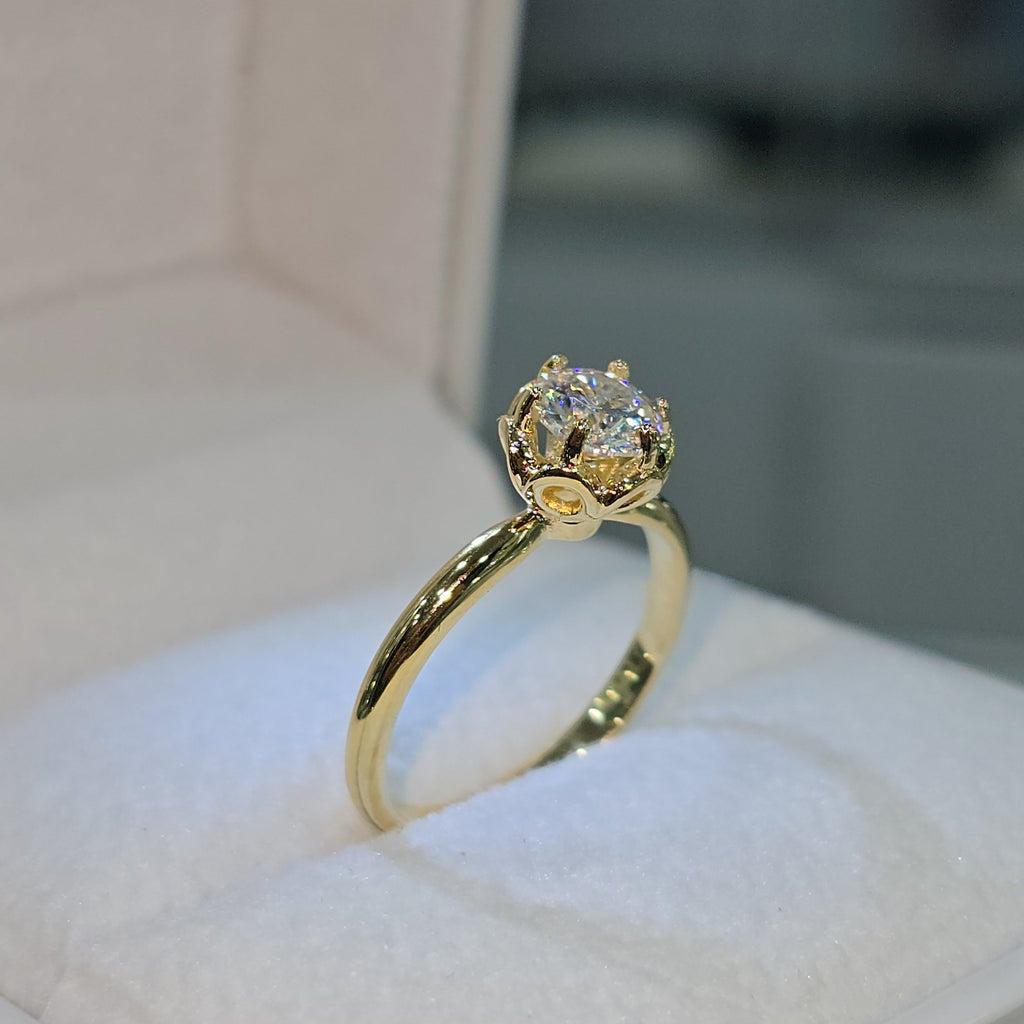 Jade18k engagement ring with a round moissanite stone in an 18k yellow gold setting with a floral-inspired crown.