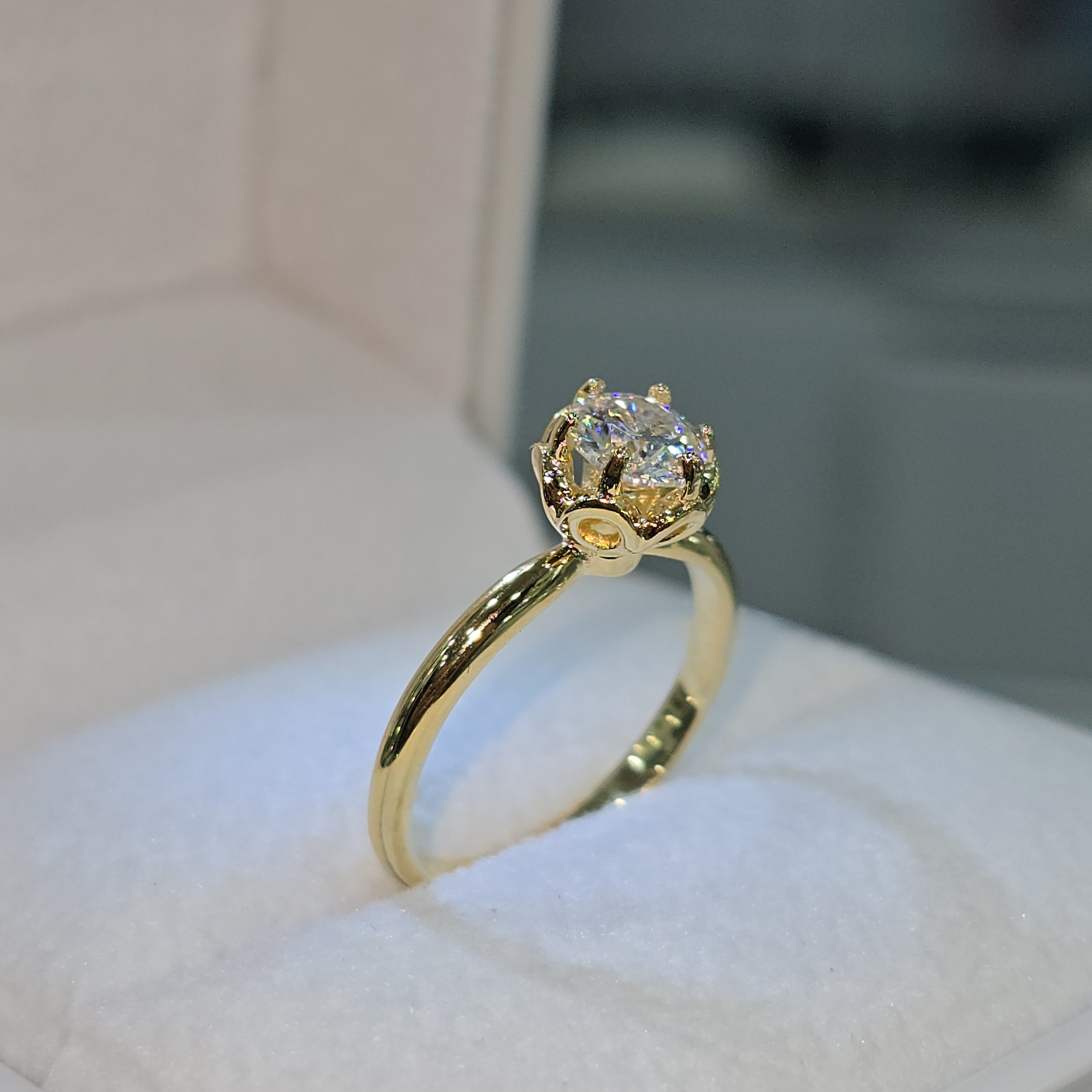 Jade18k engagement ring with a round moissanite stone in an 18k yellow gold setting with a floral-inspired crown.