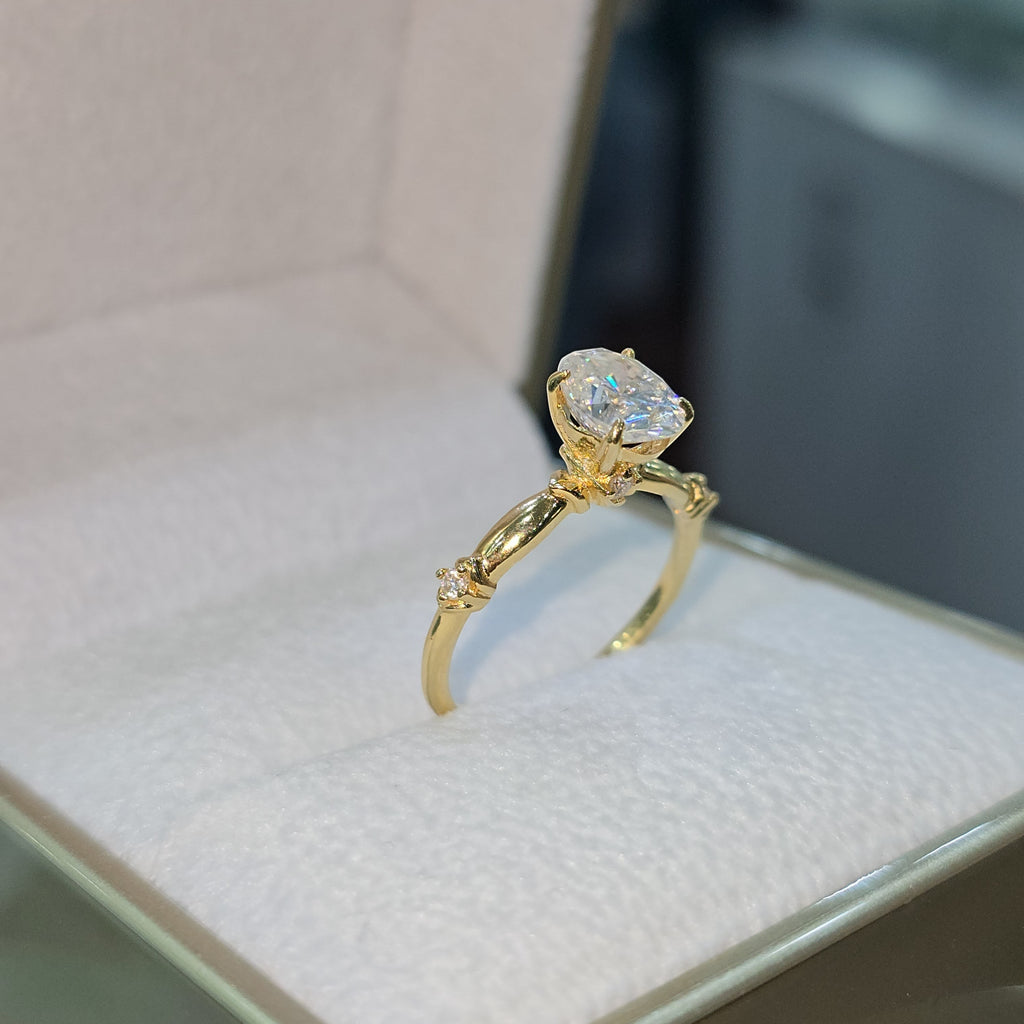 Jade18k 18k yellow gold engagement ring with a large oval moissanite center stone and small accent diamonds on the band.