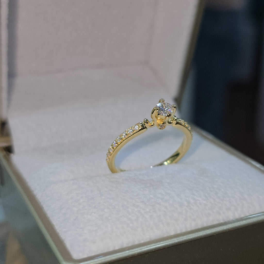 Jade18k 18k yellow gold engagement ring with a central moissanite stone and pavé-set stones along the band.
