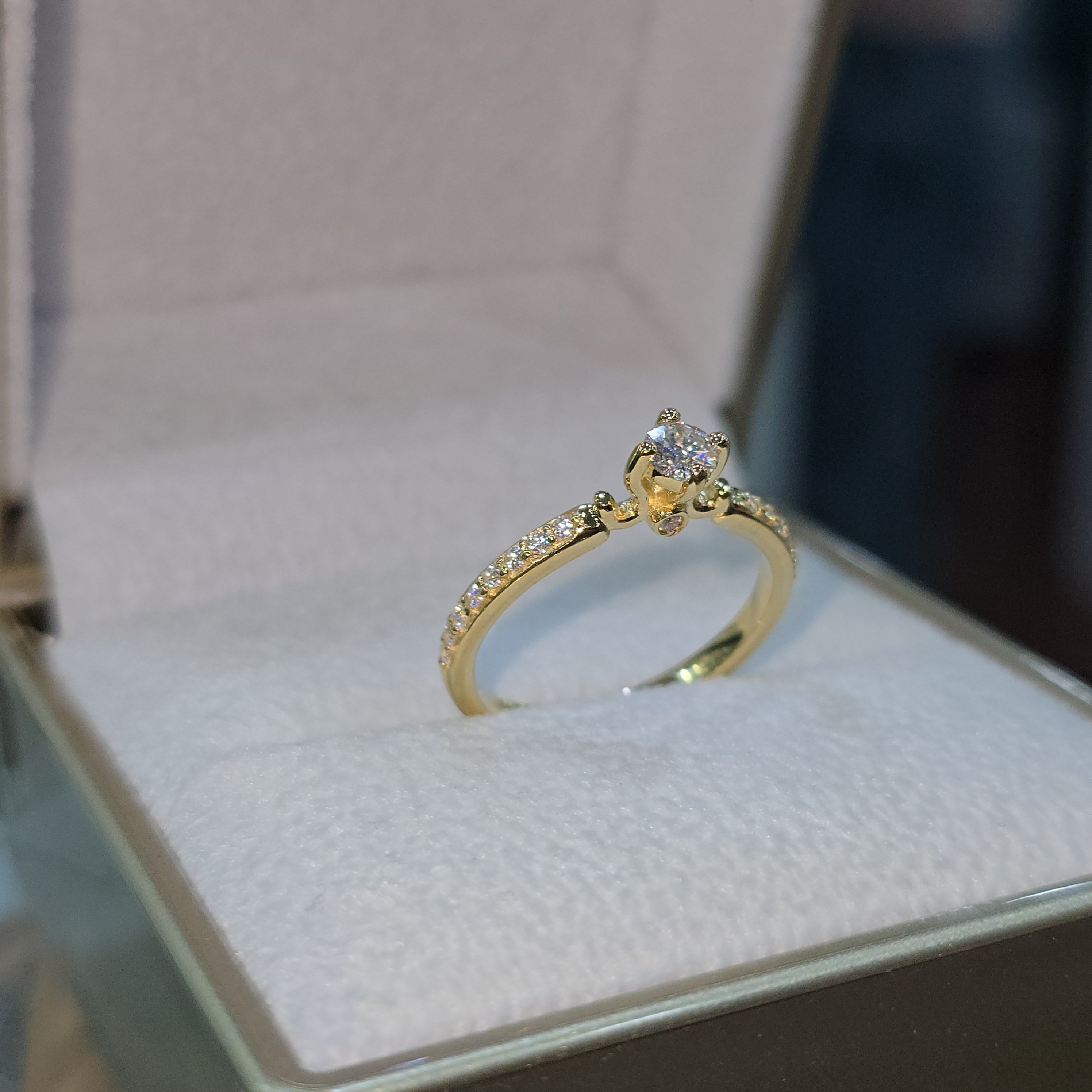 Jade18k 18k yellow gold engagement ring with a central moissanite stone and pavé-set stones along the band.