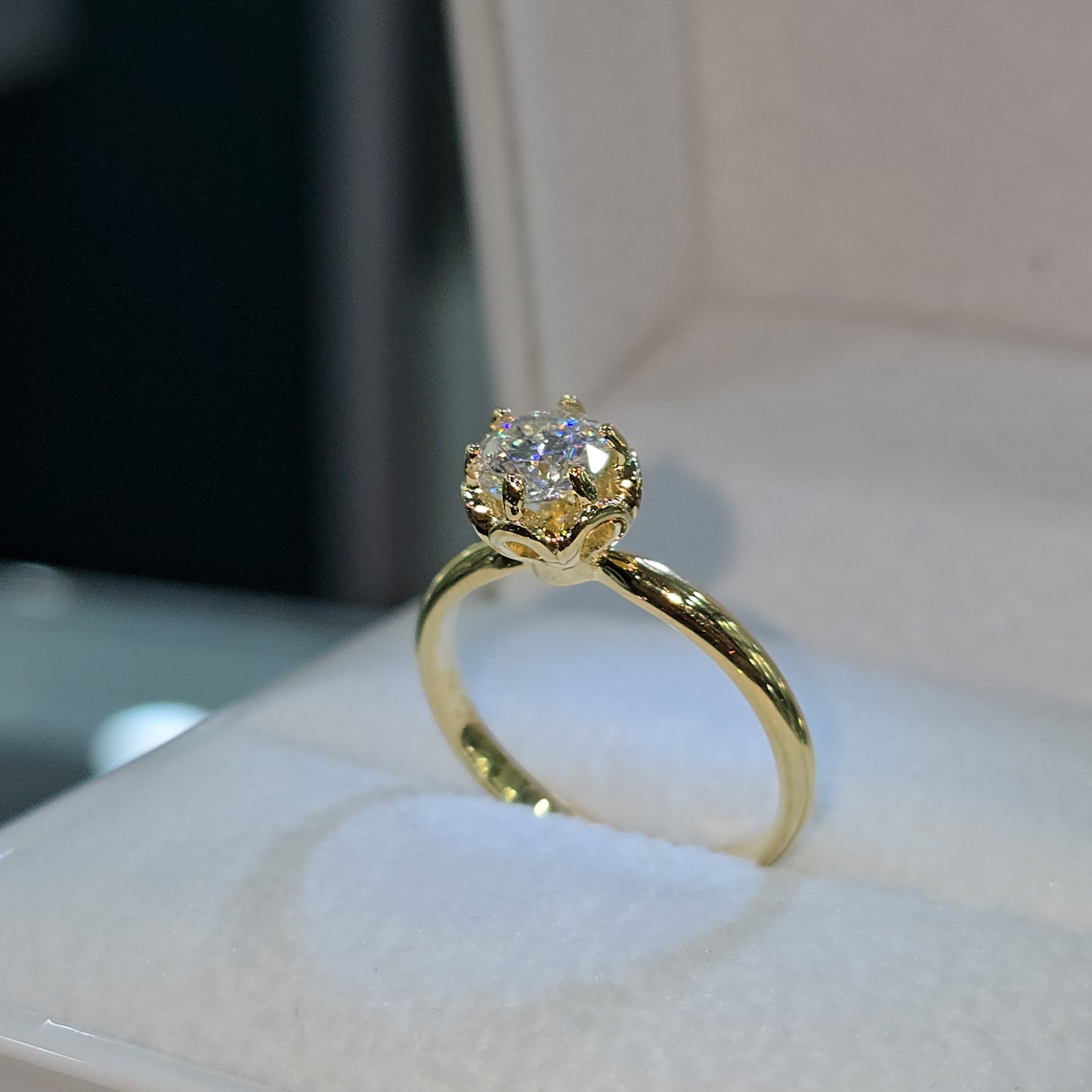 Jade18k engagement ring with a round moissanite stone in an 18k yellow gold setting with a floral-inspired crown.