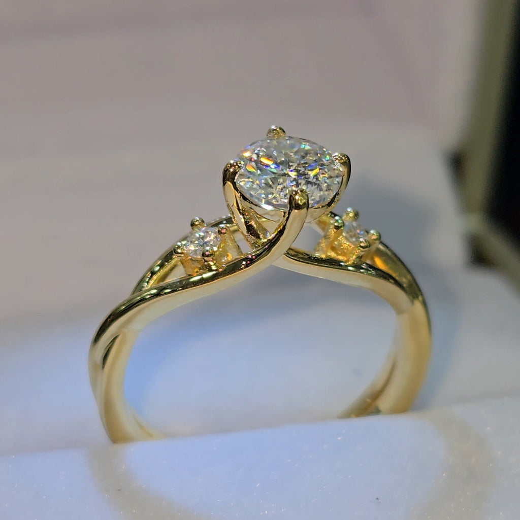 Jade18k yellow gold engagement ring with a round moissanite center stone and two small accent stones on a twisted band.