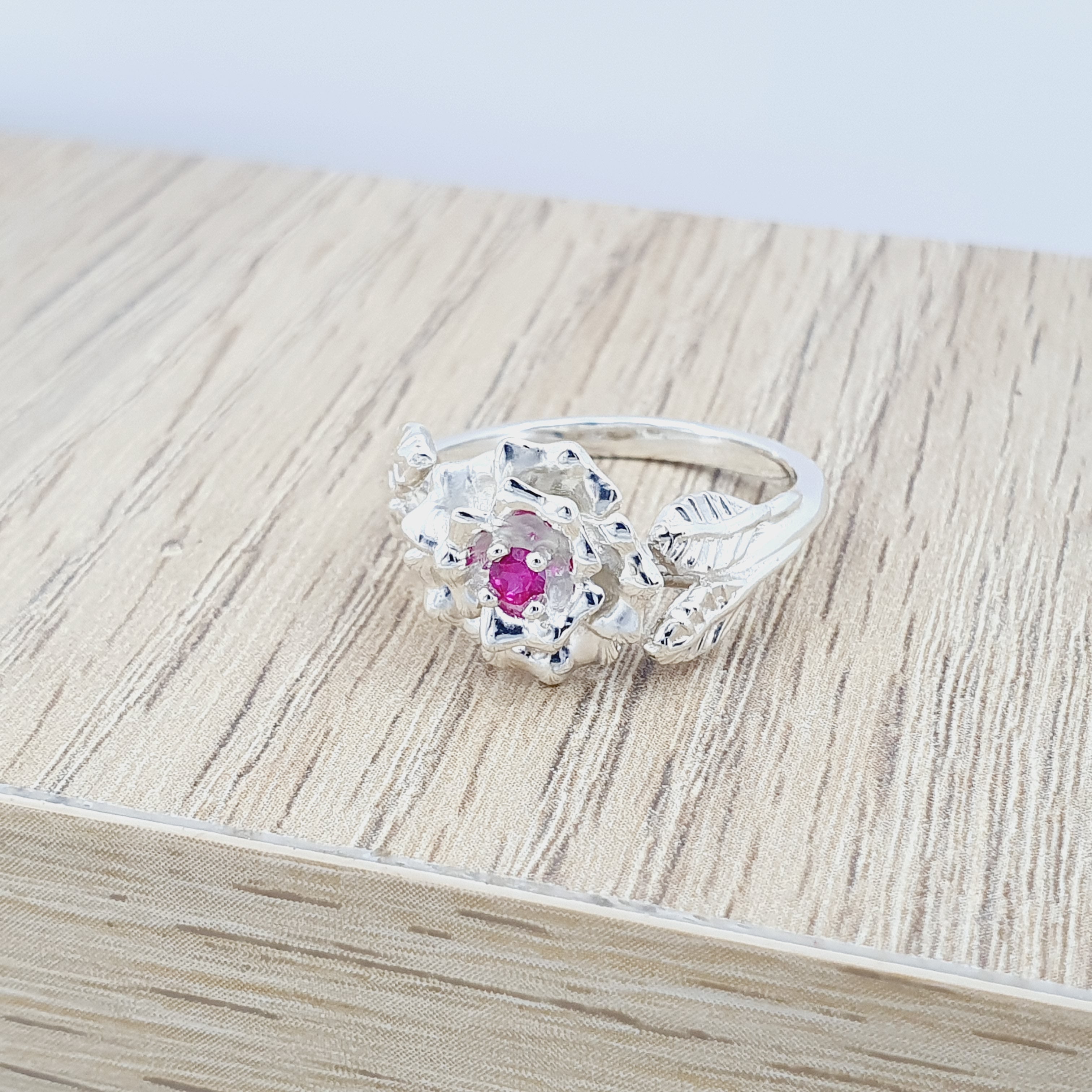 Anillo tipo flor labrada en plata con circon
