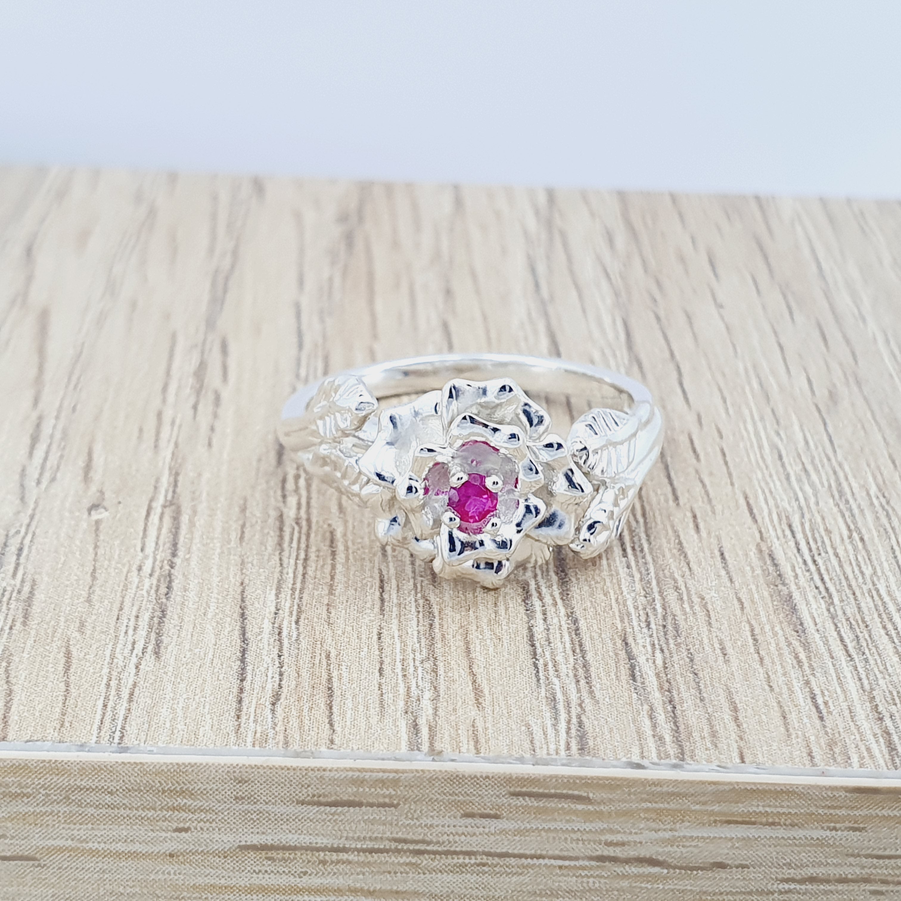 Anillo tipo flor labrada en plata con circon